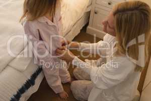 Mother helping her daughter in wearing nightwear