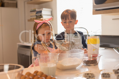 Siblings preparing food in kitchen