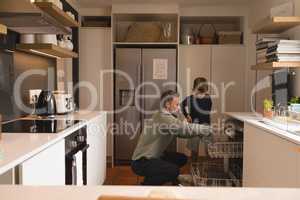Father and son arranging utensils in dishwasher
