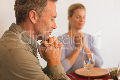 Couple praying before having food on dining table