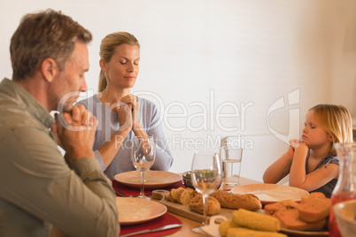 Family praying before having dinner on dining table