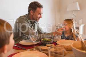 Father wiping daughters mouth with a napkin on dining table