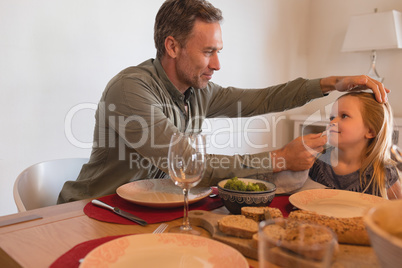 Father wiping daughters mouth with a napkin on dining table