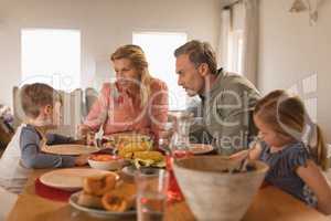 Family interacting with each other while having food on dining table