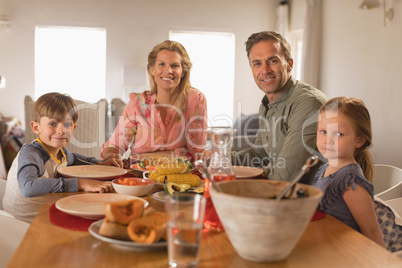 Happy family sitting on dining table at home