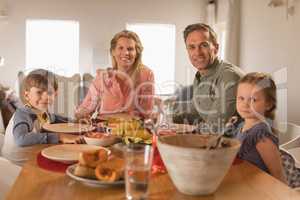 Happy family sitting on dining table at home