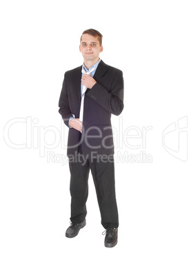 Young man standing in a suit fixing his tie