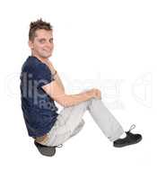 Happy young man sitting on the floor