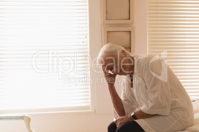 Depressed senior woman sitting in bedroom