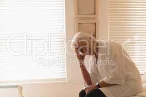 Depressed senior woman sitting in bedroom