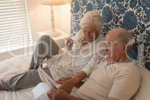 Senior couple reading newspaper in bedroom