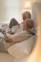 Senior couple reading newspaper in bedroom