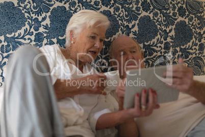 Senior couple using digital tablet in bedroom