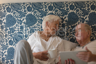 Senior couple using digital tablet in bedroom