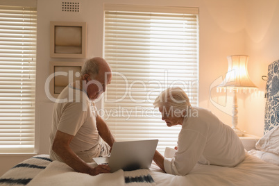 Senior couple using laptop in bedroom