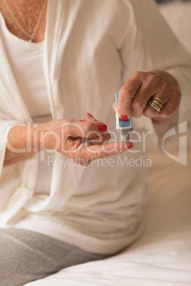 Senior woman applying cream on body
