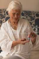 Senior woman applying cream on body in bedroom