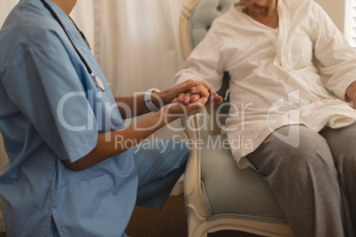 Mid section of female physician consoling senior woman