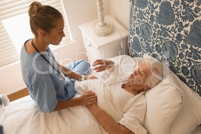 Senior woman interacting with female doctor in bedroom