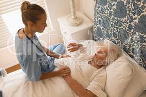 Senior woman interacting with female doctor in bedroom