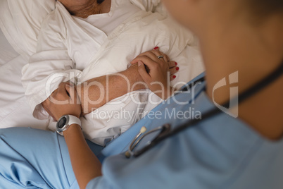 Mid section of female doctor consoling senior woman