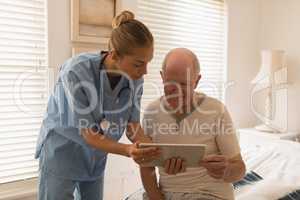 Female doctor and senior man using digital tablet