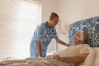 Female doctor interacting with senior man in bedroom