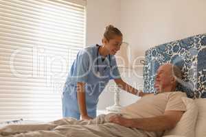 Female doctor interacting with senior man in bedroom
