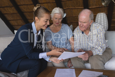 Female doctor and senior couple discussing over medical reports