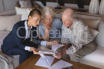 Female doctor and senior couple discussing over medical reports