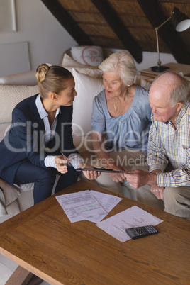 Female doctor and senior couple discussing over clipboard