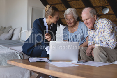 Female doctor and senior couple discussing over laptop