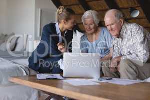 Female doctor and senior couple discussing over laptop