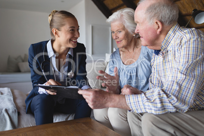 Female doctor and senior couple discussing over clipboard