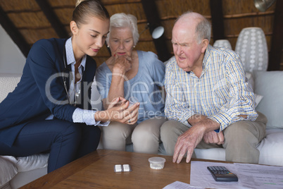 Female doctor and senior couple discussing over medicine
