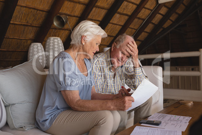 Senior couple discussing over medical bills in living room