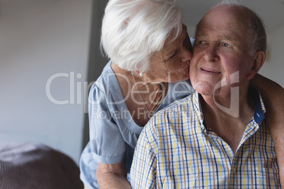 Senior woman kissing senior man at home