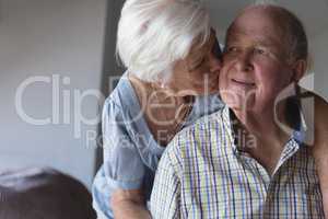 Senior woman kissing senior man at home
