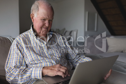 Senior man using laptop in living room