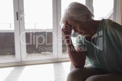 Worried senior woman sitting in living room