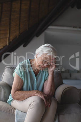 Worried senior woman sitting in living room