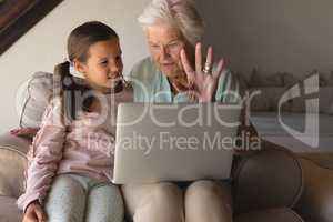 Grandmother and granddaughter discussing over laptop