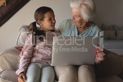 Grandmother and granddaughter discussing over laptop