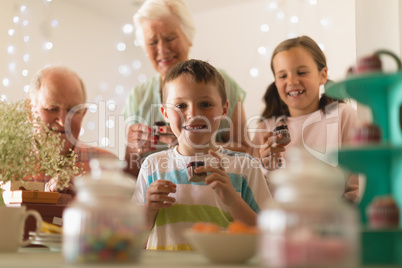 Multi-generation family having cupcakes at home