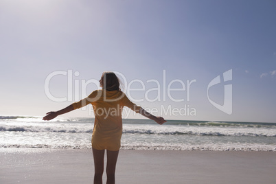 Woman standing with arms outstretched at beach