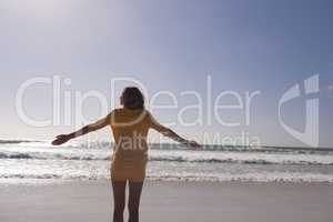 Woman standing with arms outstretched at beach