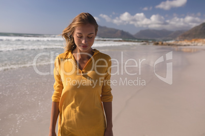 Woman standing with eyes closed on the beach