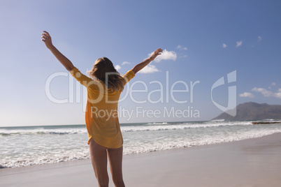 Woman standing with arms outstretched at beach