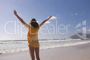 Woman standing with arms outstretched at beach