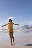 Woman standing with arms outstretched at beach